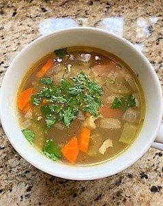 Chicken rice soup in large white soup mug sprinkled with parsley