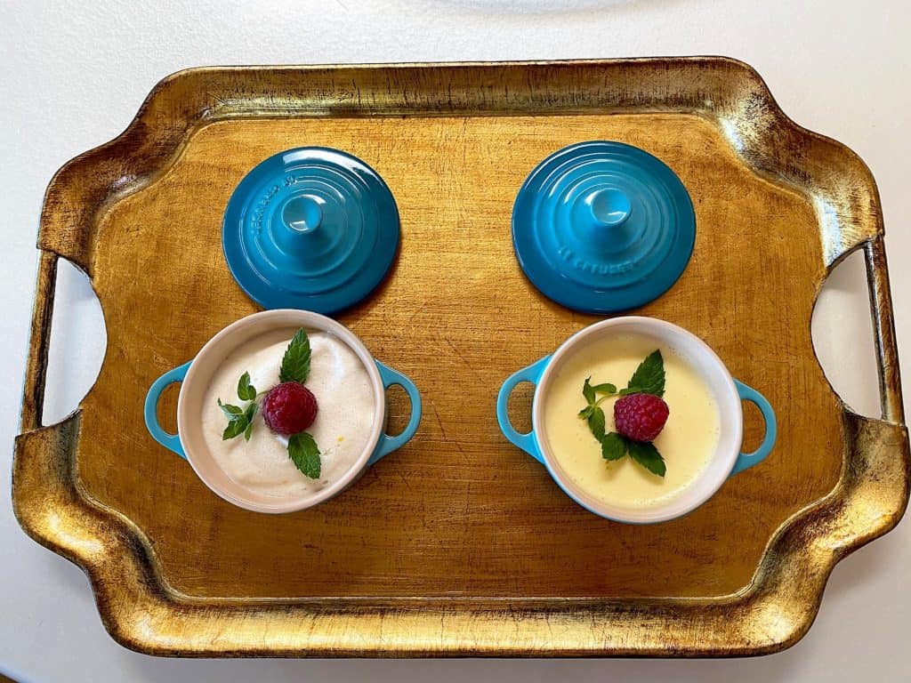 A rich, creamy lemon mousse and a light, cloudlike lemon mousse in mini teal bakers with lids on a gold tray