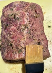 silicone pastry brush applying Dijon mustard to a pork loin