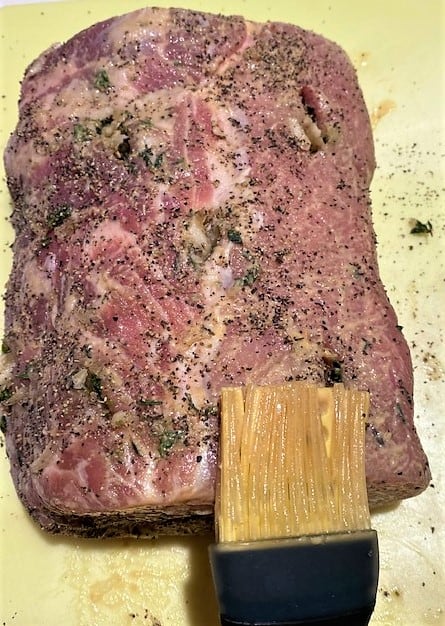 silicone pastry brush applying Dijon mustard to a pork loin