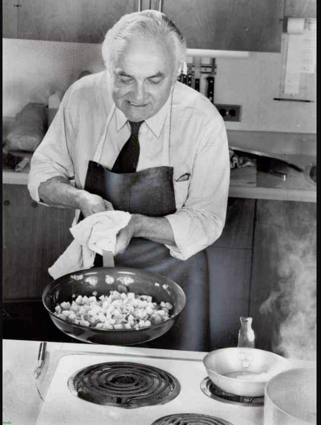 Black and white photo of Pierre Franey cooking with a large frying pan