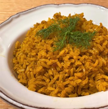 Spice-infused turmeric rice in white bowl