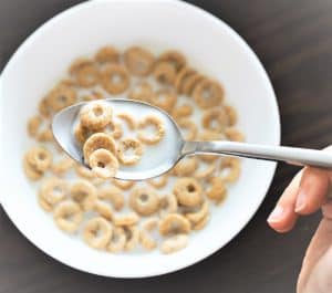 Spoon scooping cereal from a bowl full of milk and cereal