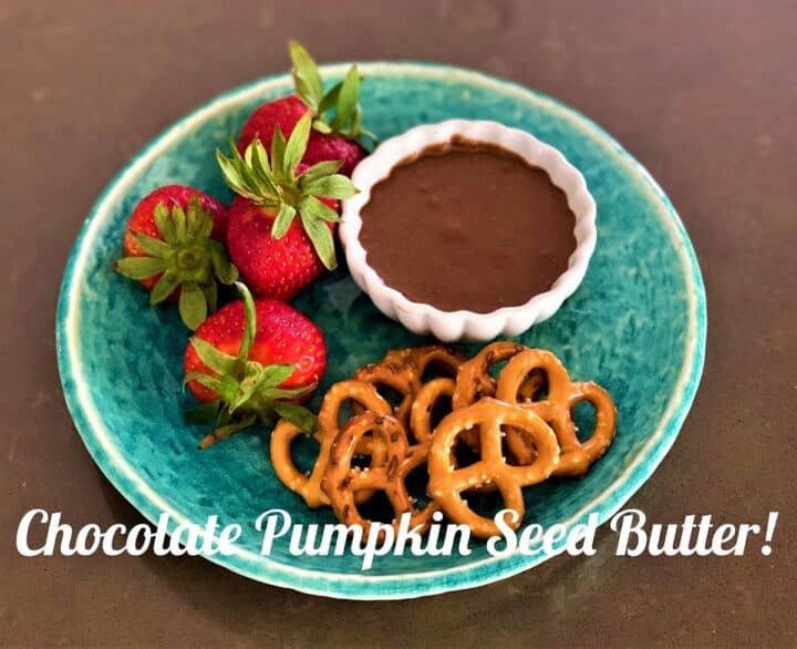 chocolate pumpkin seed butter on a green blue plate with strawberries and pretzels