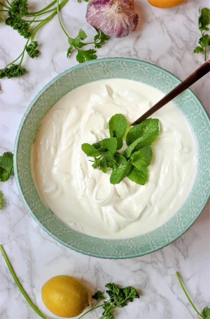Plain yogurt garnished with herbs in decorative bowl