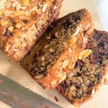 banana bread with oat flour and chocolate chunks sliced on wooden cutting board