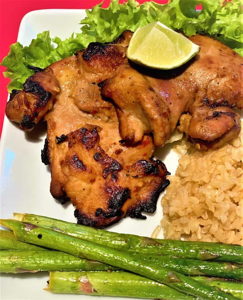 grilled boneless chicken thighs with a lime wedge, brown rice and asparagus