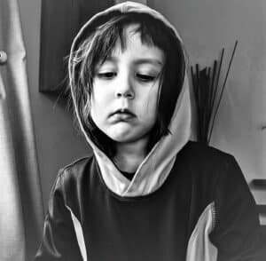 black and white photo of sad looking child in a hood