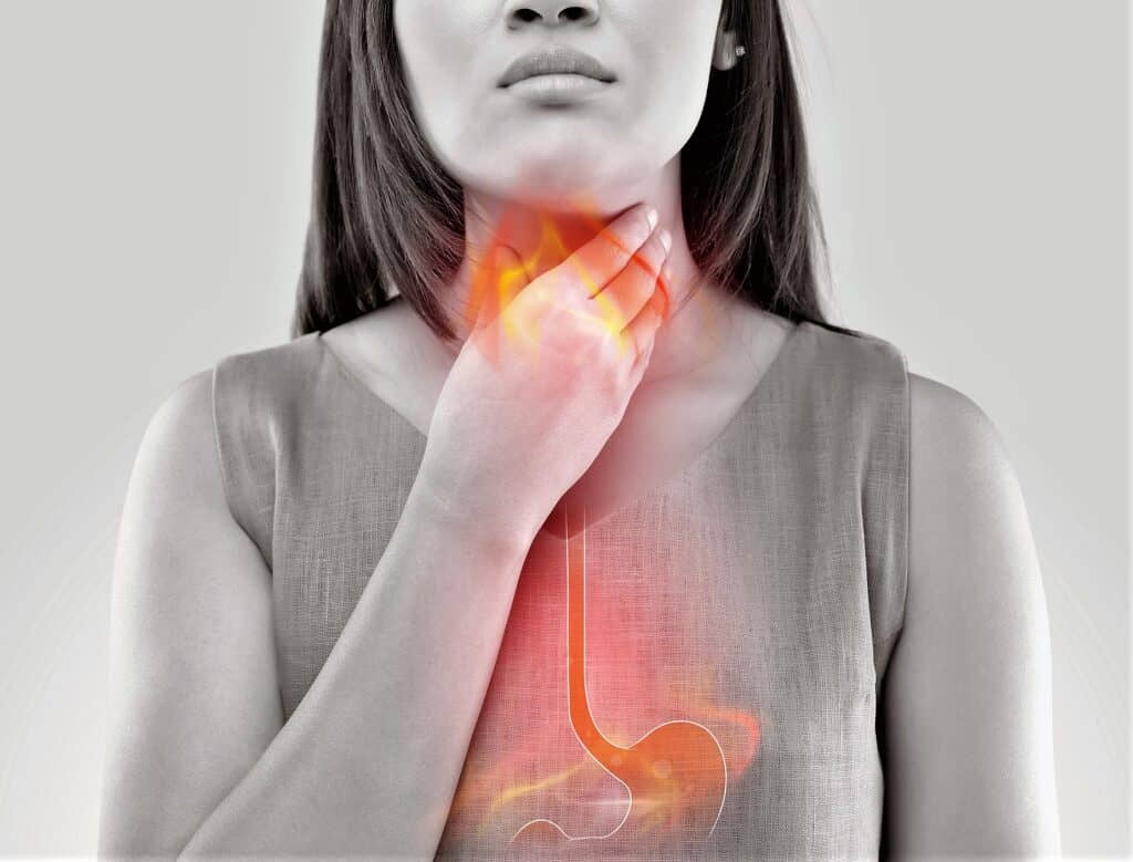 Black and white woman's upper body with hand clutching throat and digestive tract in red.