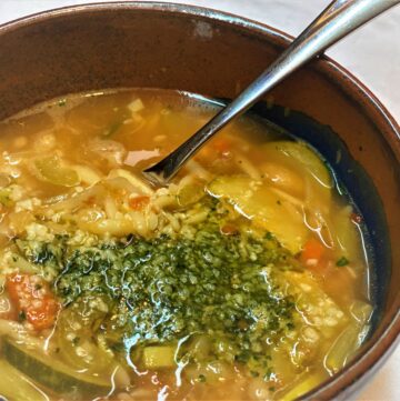 A bowl of Minestrone di Verdure, an Italian soup topped with pesto