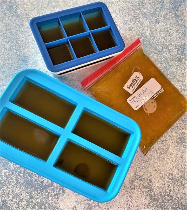 Veggie scraps broth in storage containers, flat zip bag, blue ice cube tray and larger blue-green Souper Cube tray