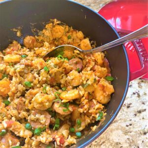 Healthy jambalaya with andouille sausage and brown rice in red Dutch oven on a granite countertop