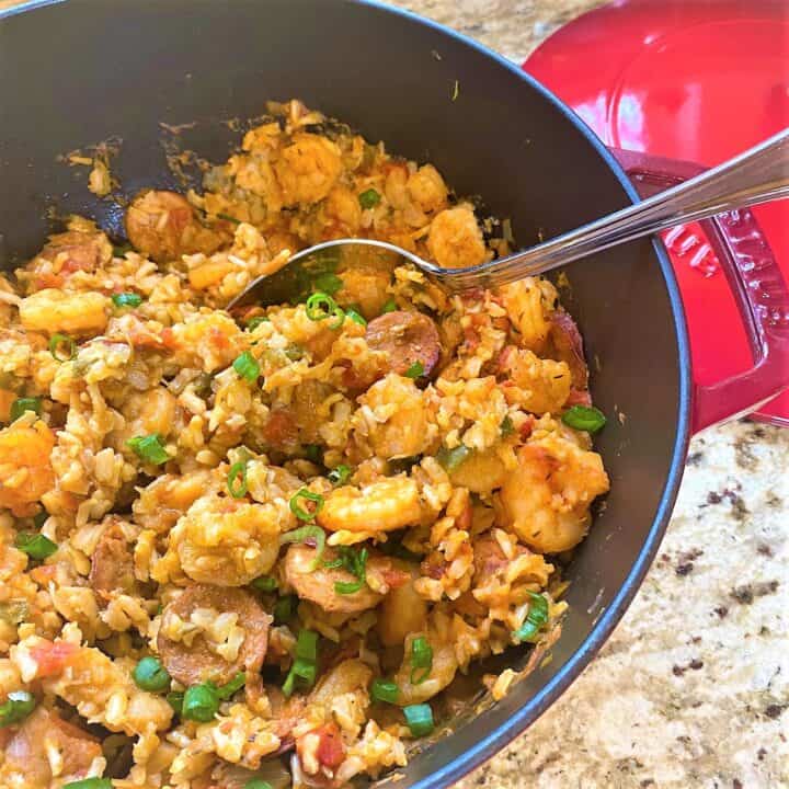 Healthy jambalaya with andouille sausage and brown rice in red Dutch oven on a granite countertop