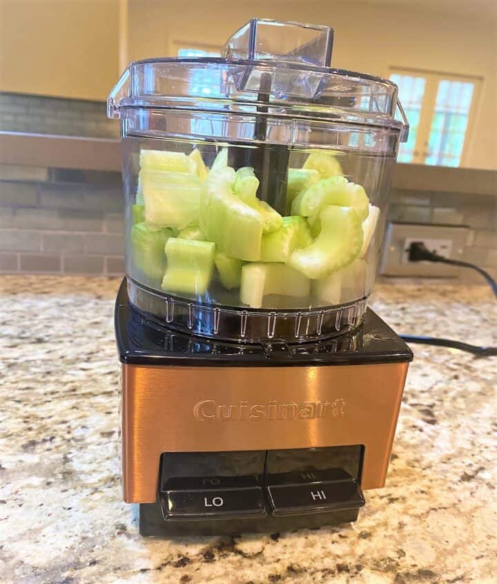 Mini Cuisinart food processor filled with celery chunks for healthy jambalya