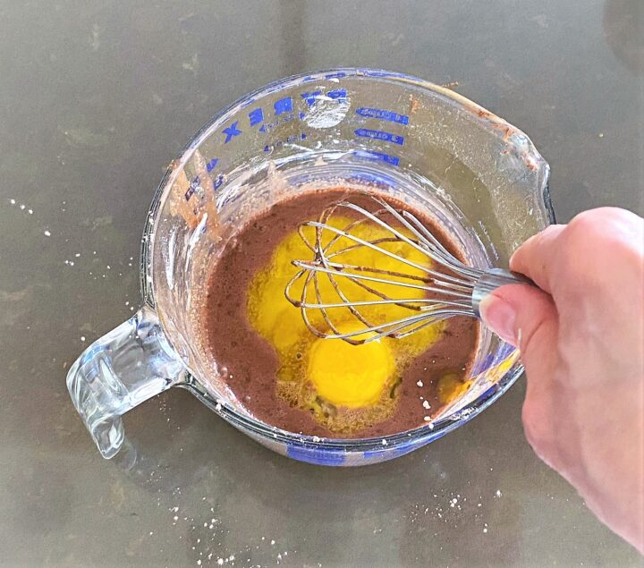 Whisking egg yolks into no bake chocolate pie ingreidients in a large glass measuring cup