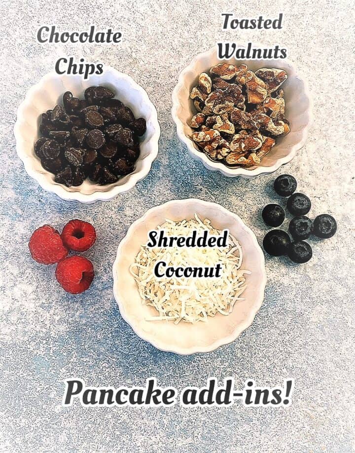 Chocolate chips, walnut pieces, shredded coconut with blueberries and raspberries on a mottled blue countertop