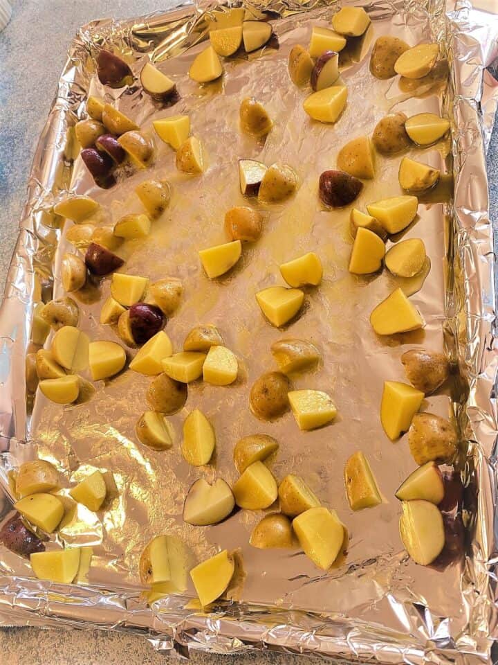 Small yellow potato chunks spread on sheet pan lined with aluminum foil