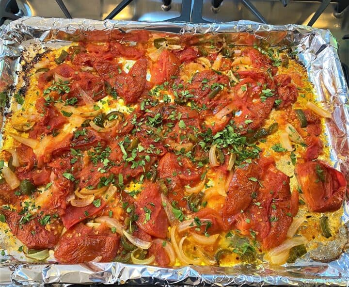 Roasted smashed tomatoes, with green peppers, onion, and seasonings including a green sprinkle of cilantro; all on sheet pan.