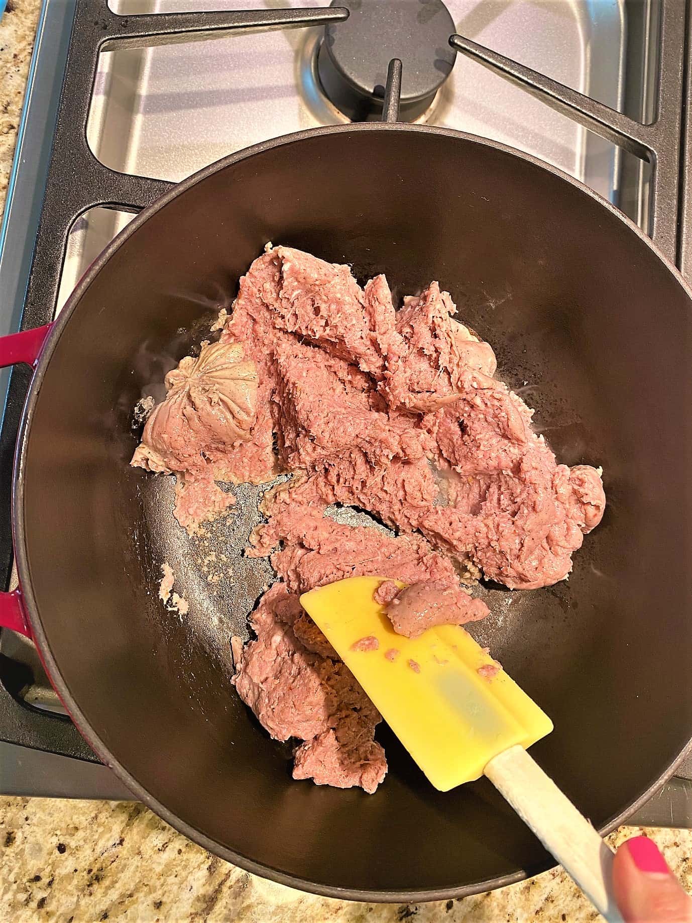 Browning pinkish, raw, ground turkey sausage in Dutch oven with a silicone and wood spatula