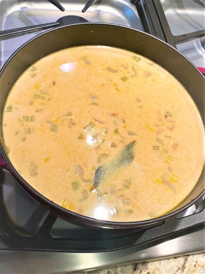 Off-white and Creamy Corn and Sausage Chowder Using evaporated milk in a dark Dutch oven on the stovetop