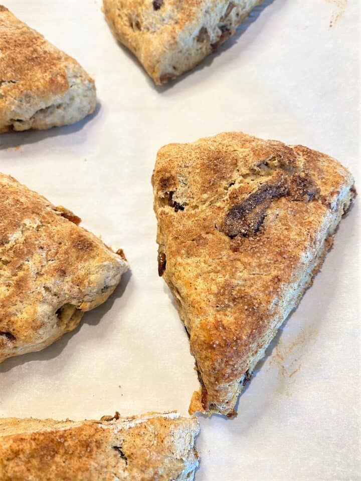 Close up of wedge-shaped date scones on parchment paper