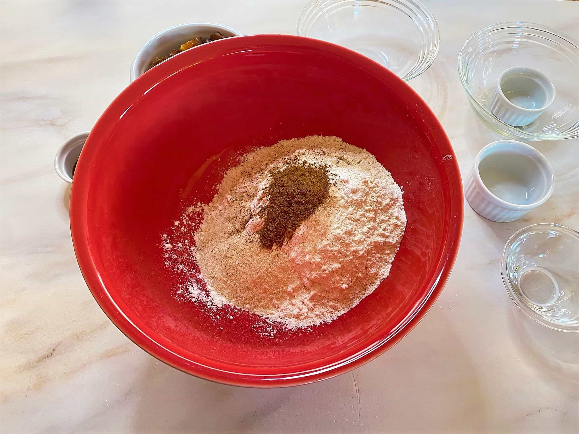 Scarlet bowl with flour and dry ingredients for scones inside including cinnamon on top