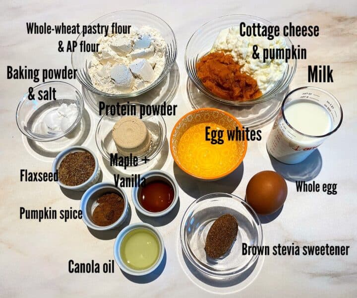 Dry and wet ingredients for pumpkin protein waffles with labels on a white marble background