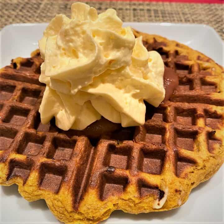 ragged edge, deeply golden round waffle with four sections and whipped cream on top