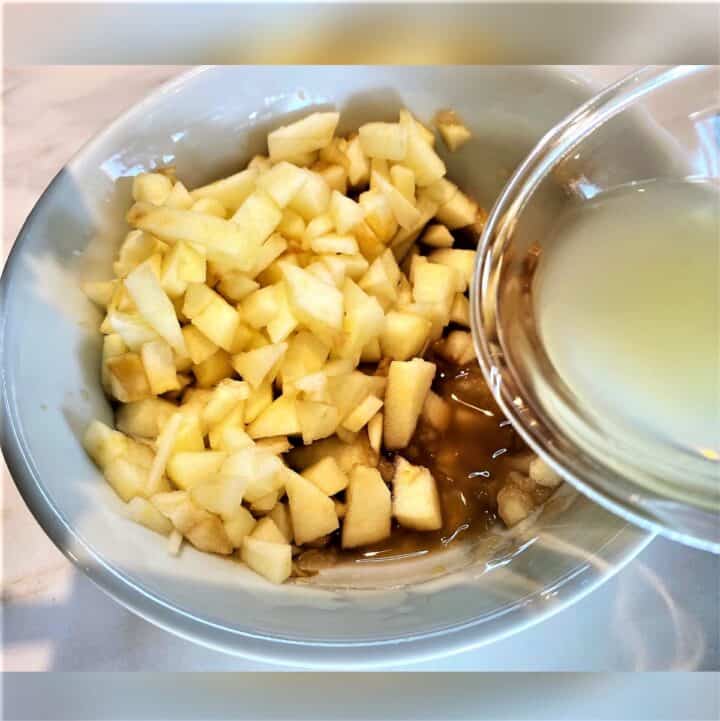 Pouring lemon juice into a bowl with chopped apple and pear mush.