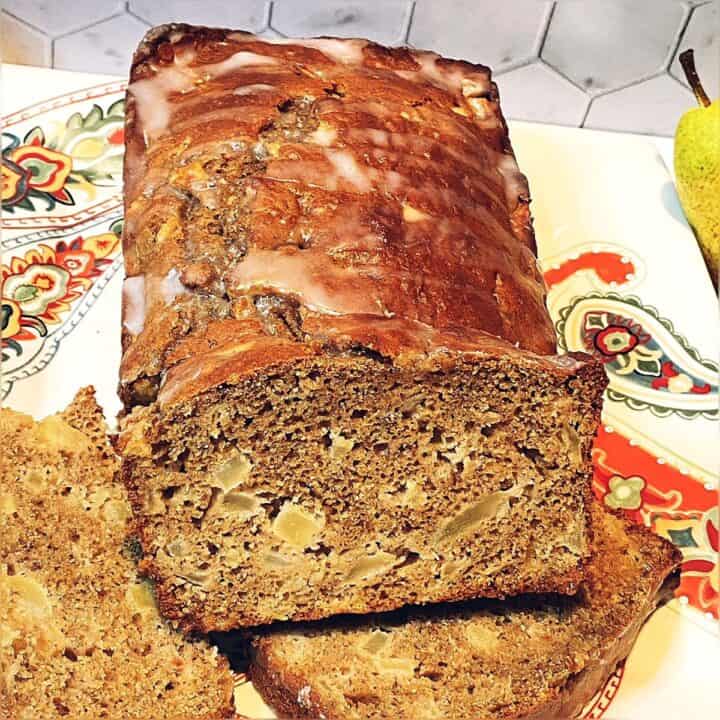 Slices of apple pear bread with the loaf on a plate with a paisley pattern.