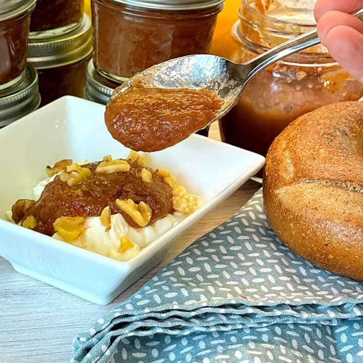 Small jars of pear caramel-colored pear butter surround a square white bowl holding white yogurt topped with pear butter, which also drips thickly from a spoon.