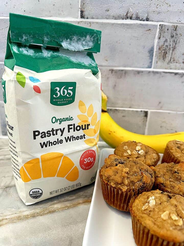 Paper bag of organic whole wheat pastry flour with Whole Foods label on the left and plate of berry muffins on the right.