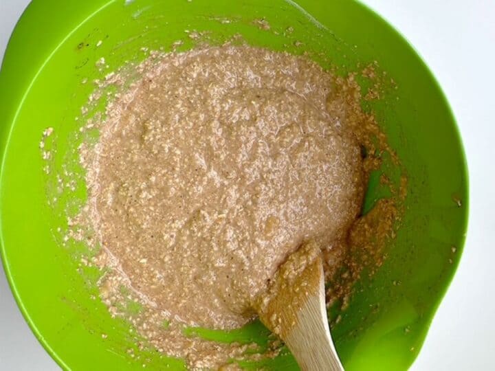 Beige nubbly mix of oat flour and wet ingredients in lime green mixing bowl.