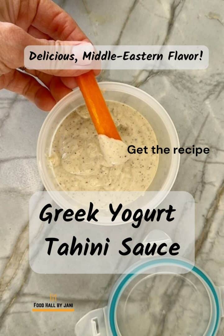 Carrot stick dips into a a round opaque container full of creamy tahini sauce.