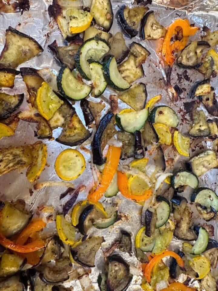 Yellow squash, zucchini half moons, strips of orange bell pepper look cooked and caramelized in this closeup.