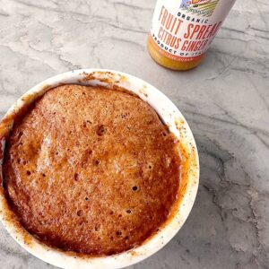 Round amber Honey Almond Butter Cake on a gray marble counter with citrus fruit spread.