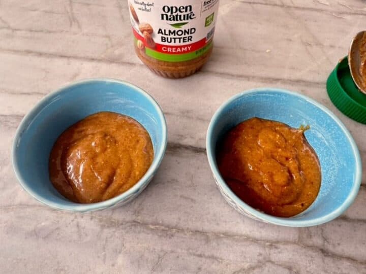 Two blue-green ramekins filled with brown honey almond butter batter.