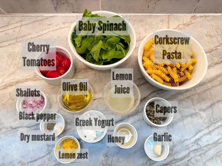 Curly pasta, baby spinach leaves, cherry tomatoes, lemon juice, and other ingredients for a Pasta Salad with Greek Yogurt Dressing.
