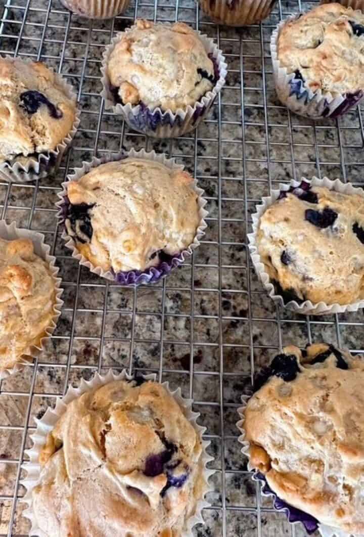 Blueberry Muffins in semi-opaque liners on a cooling rack.