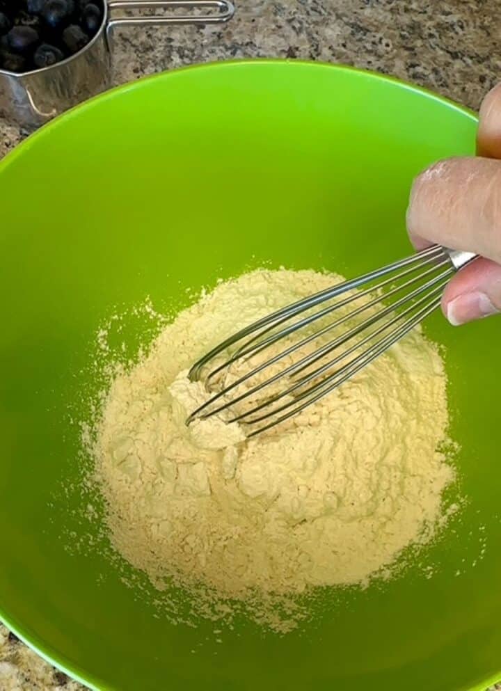 Whisking flour and dry ingredients in a lime green bowl.