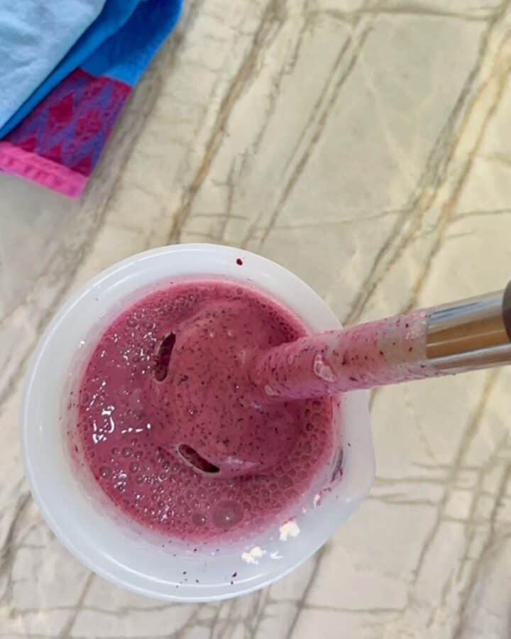 Tall opaque silicone container with purplish blueberry-Greek yogurt puree and immersion blender.