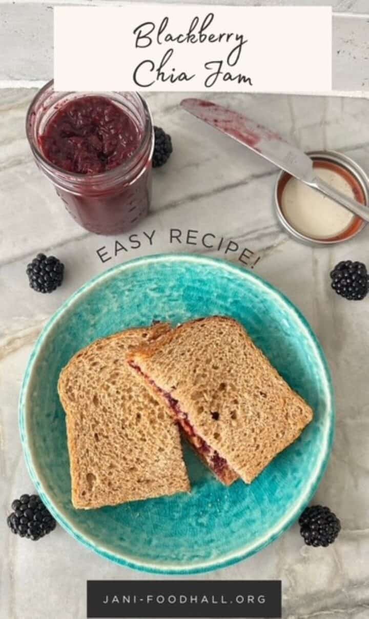 A pb&j sandwich on brown wheat bread is cut in half on a green plate.