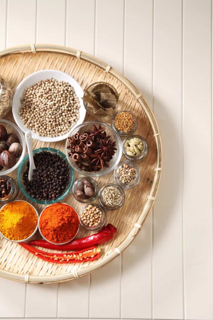 Round beige tray filled with a variety of loose, colorful spices.