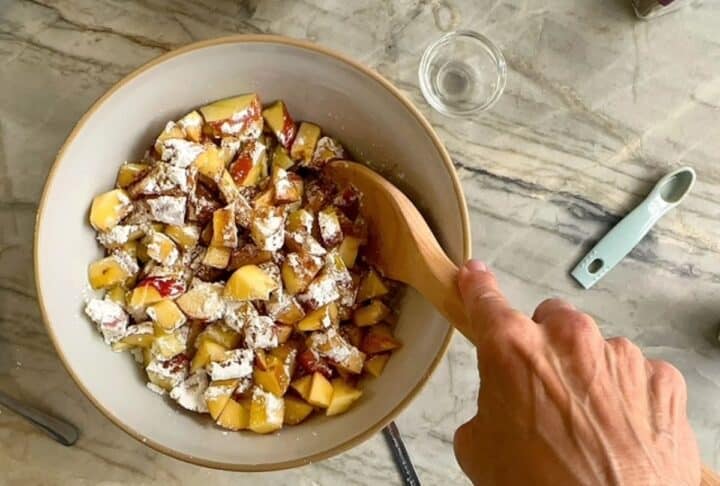 Chopped apple cubes in bowl with white cornstarch on top.