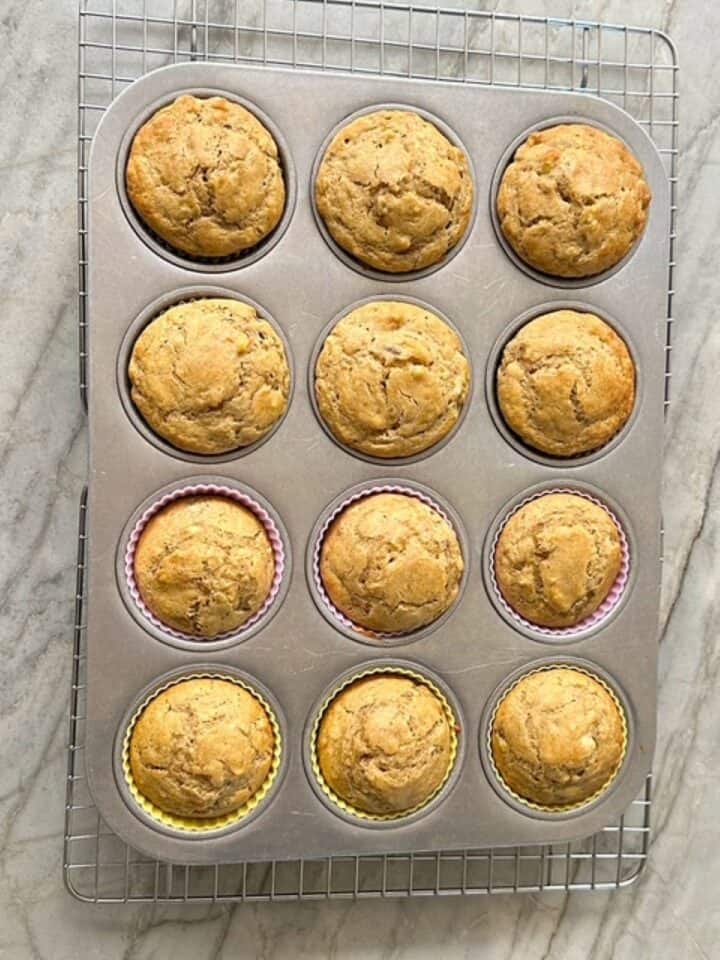 Golden baked banana muffins (gluten-free) fill a gray muffin tin.