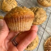 A golden brown banana muffin (gluten-free) is displayed in a hand.