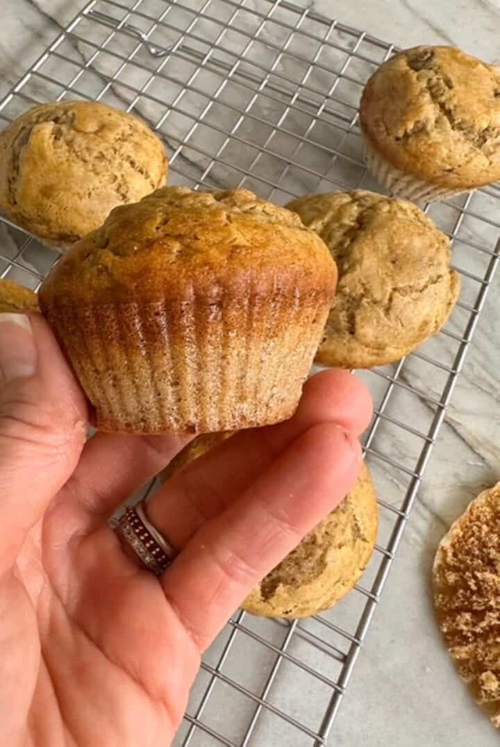 A golden brown banana muffin (gluten-free) is displayed in a hand.
