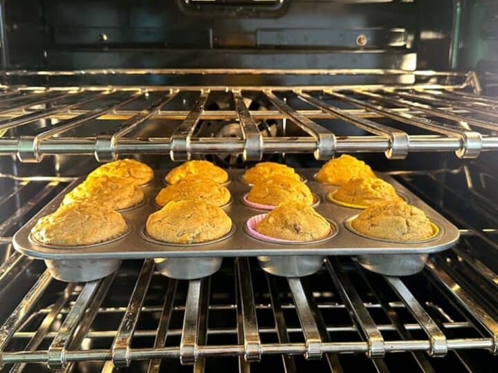 View of golden banana muffins baking in dark oven cavity.