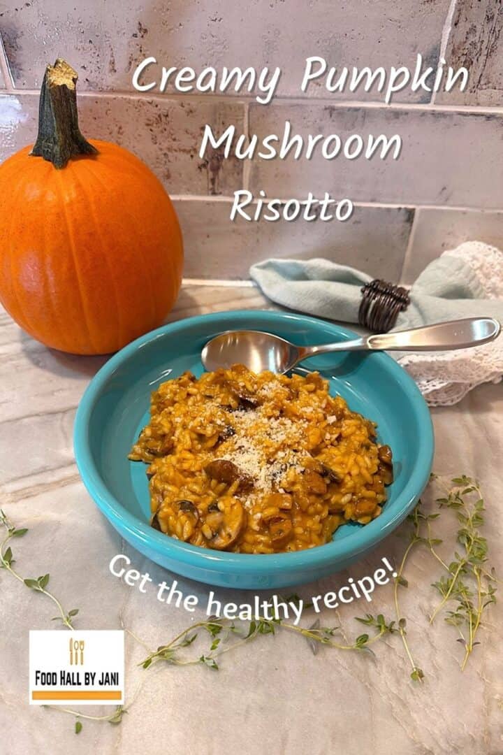 A creamy,golden-hued risotto in a round, blue dish sits in front of a small orange pumpkin.