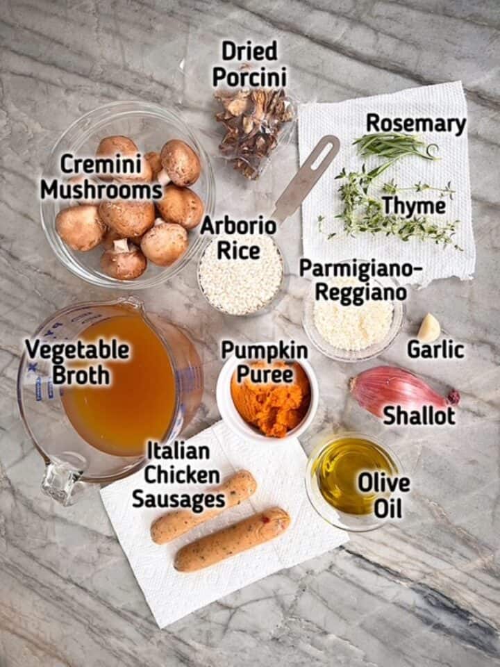 Fresh brown mushrooms, golden veggie broth, white Arborio rice, orange pumpkin puree, and more ingredients for risotto on a gray countertop.